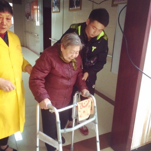 图为：参加志愿活动的学生帮扶老人